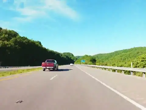 An interstate highway between tree lines under a blue sky