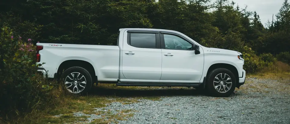A white pickup parked by pine trees